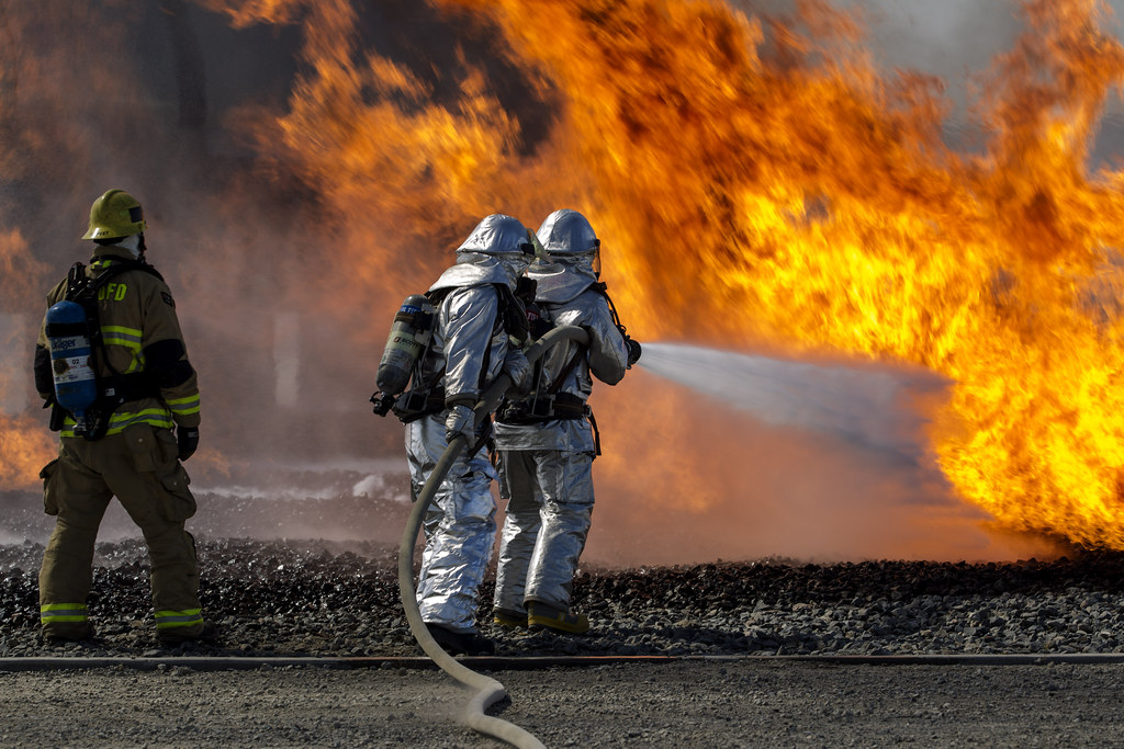 Two firefighters extinguish a burning aircraft.